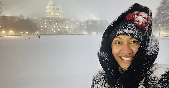 A woman standing in snow in front of Capitol Hill
