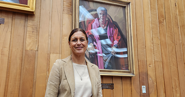 A woman standing in front of a painted portrait of a woman